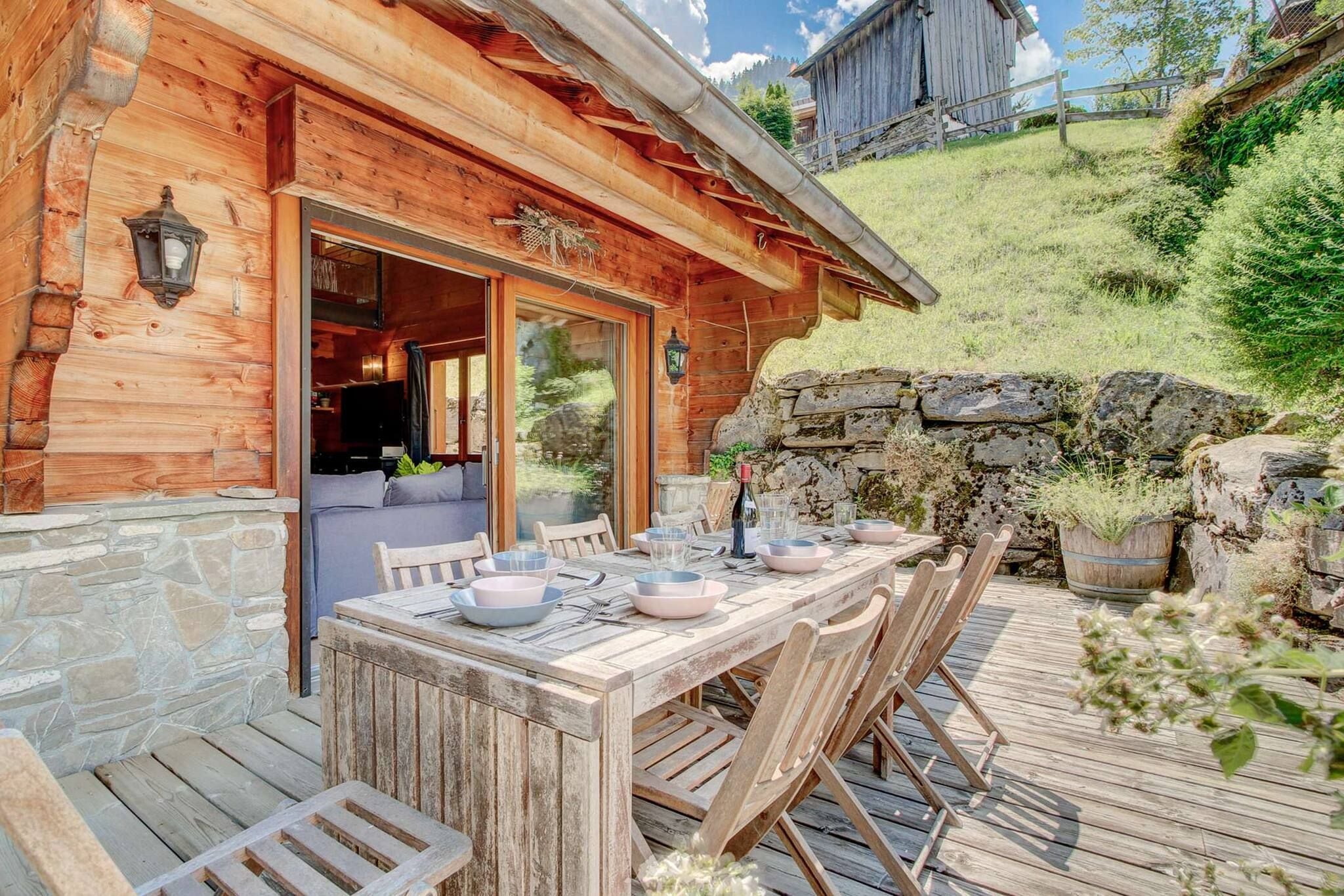 Una cabaña de madera con un muro de piedra y una zona de comedor al aire libre.