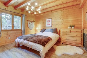 Een slaapkamer in een houten blokhut met een bed, een kaptafel en een macramé wanddecoratie.