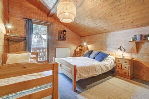 A cozy wooden room with a bed, bedside table, and a window.