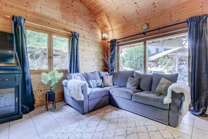 Una habitación acogedora con un sofá modular, un televisor y un ventanal con cortinas.