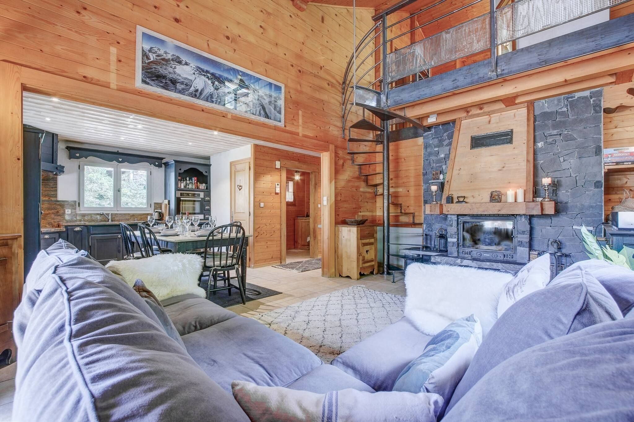 A cozy cabin interior with a dining area, a fireplace, and a staircase leading to an upper level.
