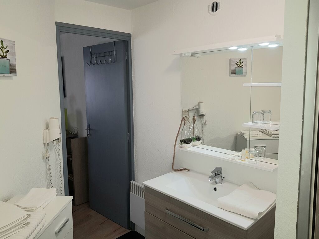 Ein modernes Badezimmer mit einem weißen Waschbecken, einem großen Spiegel und einem Handtuchhalter.