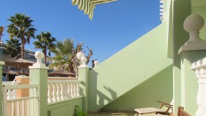 A sunlit patio with a white fence, a wooden bench, and a palm tree in the background. - bungalow with terrace (Gran Alacant)