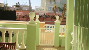 A balcony with a green and white striped awning, a white gate, and a table with a patterned tablecloth. - bungalow with terrace (Gran Alacant)
