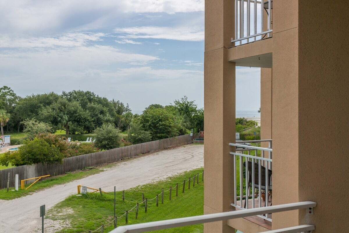 Un balcon donnant sur un espace clos et des arbres.