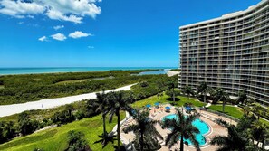 A resort with a large pool, a beach, and a view of the ocean.