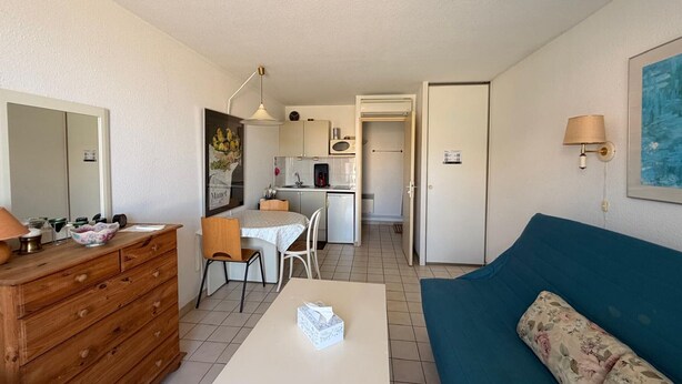 A compact living space with a kitchenette, a dining area, a sofa, and a wooden dresser. - Air-conditioned studio with parking in Banyuls-sur-Mer near the sea (Banyuls-sur-Mer)