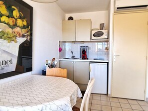 Ein kleiner Raum mit einem Bett, einer Küchenzeile und einem Kühlschrank.