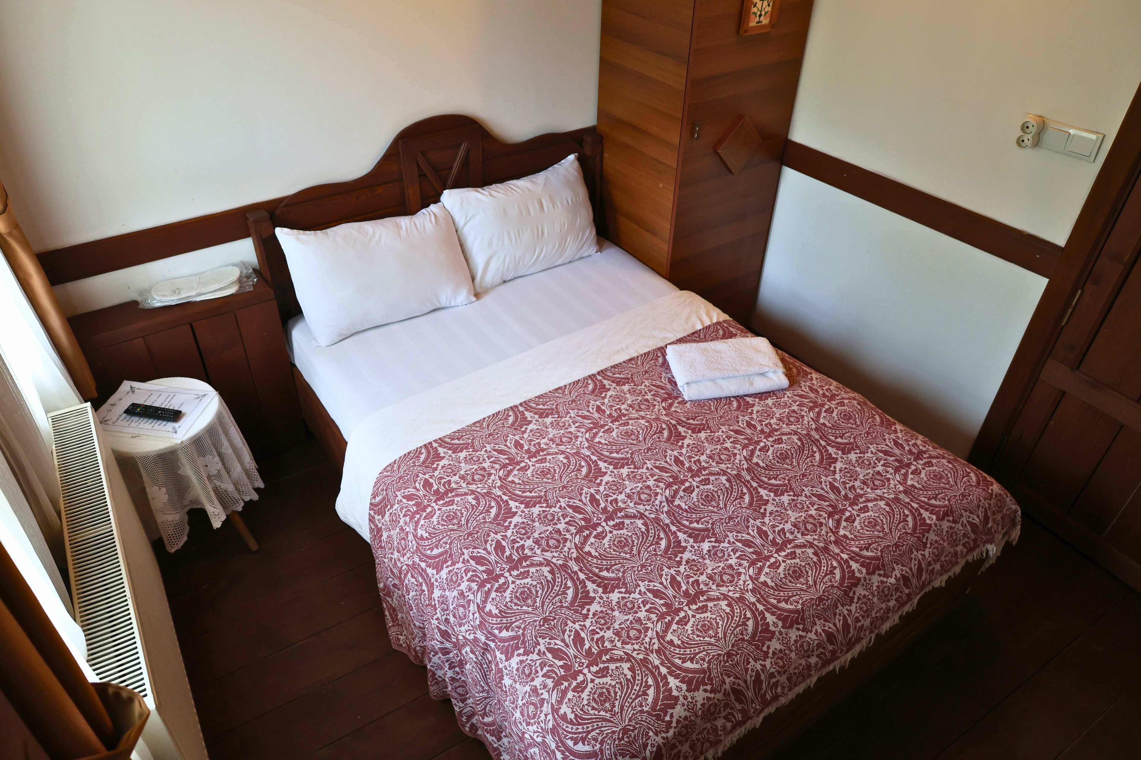 Una cama bien hecha con una colcha estampada, un cabecero de madera y una mesita de noche con una lámpara.