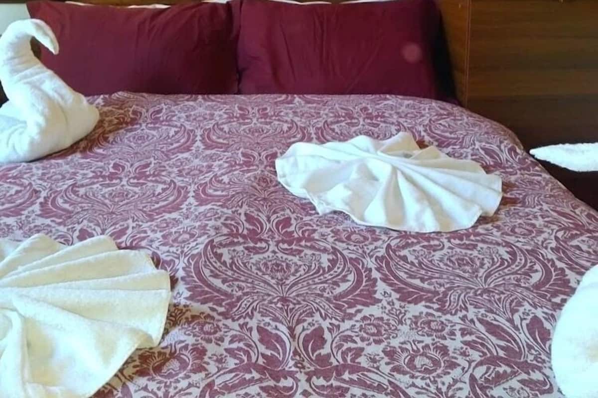A bed with a patterned bedspread, two pillows, and two towels arranged on the bed.