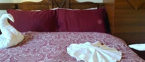 A bed with a patterned bedspread, two pillows, and two towels arranged on the bed.