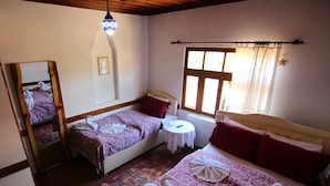 A room with two beds, a mirror, a small round table, and a window with curtains. - Ahşena Bağ Badeli Konak Safranbolu (Safranbolu)