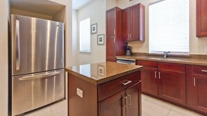 A kitchen with stainless steel appliances, wooden cabinets, granite countertops, and a window with blinds. - Bay Front: Gradual-Entry Pool: Boat Slip (South Padre Island)