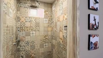 Une douche avec des carreaux décorés et une petite fenêtre.