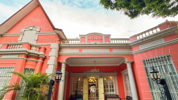 Un bâtiment rouge avec une enseigne portant le nom « Avelina » et une entrée carrelée.