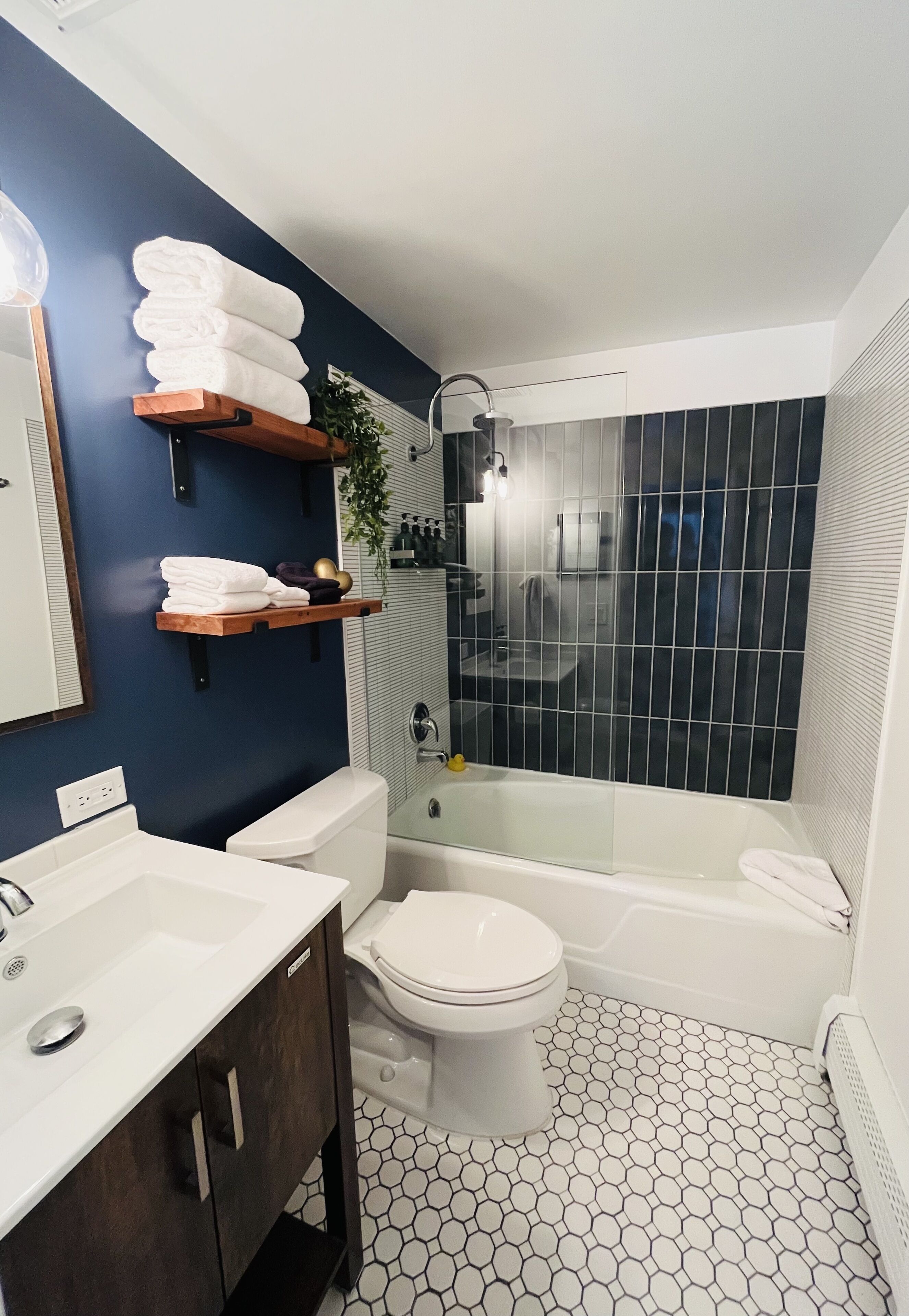 Une salle de bain moderne avec un lavabo blanc, des meubles en bois foncé, des toilettes blanches, une baignoire et une douche à parois de verre.