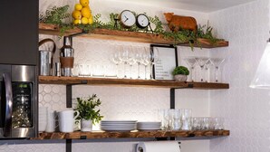 Una cocina con estantes de madera que contienen cristalería y un reloj.