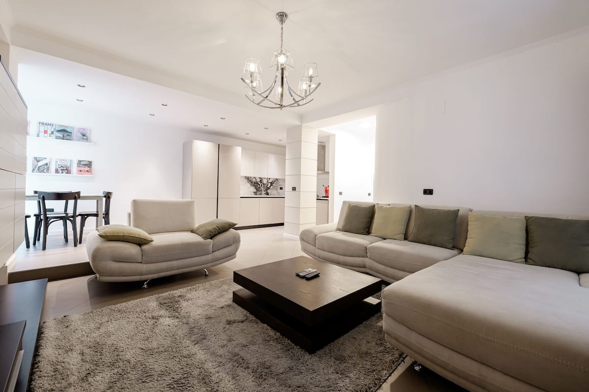 Ein modernes Wohnzimmer mit einer Sofagarnitur, einem Couchtisch und einer Chandelüster.