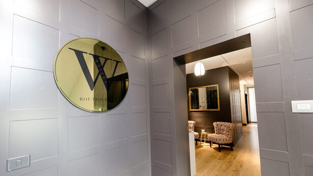 A hallway with a circular mirror featuring a large 'W' logo and the text 'BOUTIQUE WHISKEY'. - Boutique Hotel Whisky (Tirana)