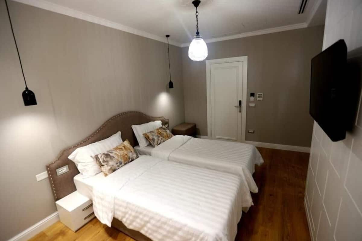 Ein Schlafzimmer mit zwei Betten, einem Nachttisch, einem Fernseher und einer Tür.