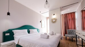 A neatly made bed with white linens, a teal upholstered headboard, and a white bedside table with drawers. - Boutique Hotel Whisky (Tirana)