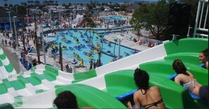 Parque acuático con múltiples piscinas y toboganes, rodeado de palmeras y un cielo despejado.