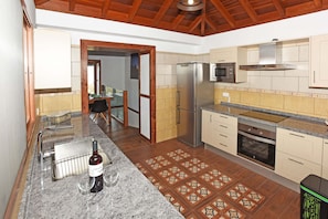 A kitchen with a stainless steel refrigerator, microwave, oven, and a dining area with a table and chairs.