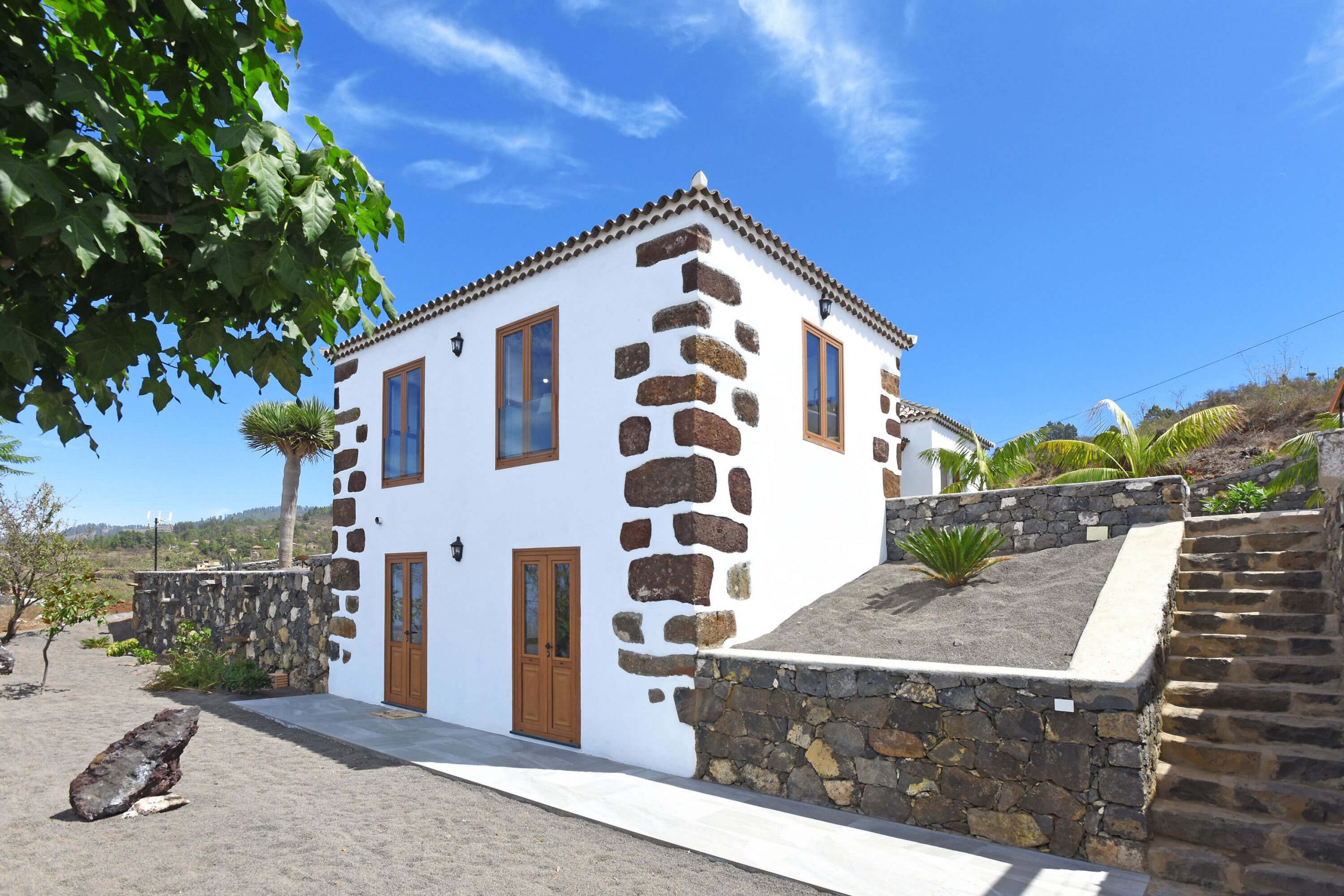 A white building with stone accents, a wooden door, and a stone staircase.