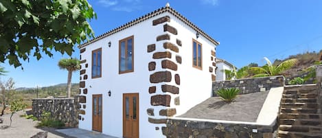 Un bâtiment blanc agrémenté de détails en pierre, une porte en bois et un escalier en pierre.