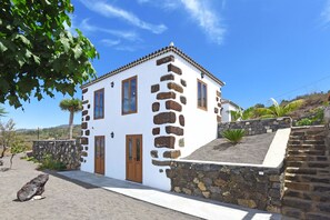 A white building with stone accents, a wooden door, and a stone staircase.