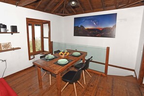 A wooden dining table with black chairs, a glass partition, and a framed landscape painting on the wall. - Casa La Florida en Puntagorda (Tijarafe)