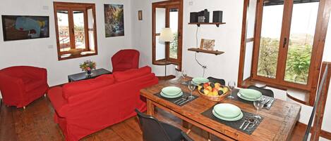 Un coin repas avec une table en bois dressée pour quatre personnes, entourée de canapés rouges et de chaises noires.