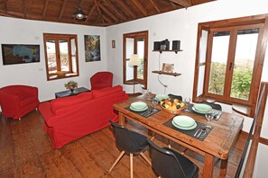 A dining area with a wooden table set for four, surrounded by red sofas and black chairs.