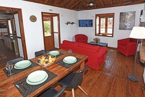 Ein Essbereich mit einem Holztisch, gedeckt für vier Personen, roten Sofas und einem Fernseher an der Wand.