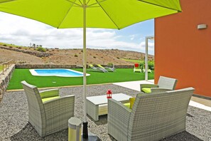 An outdoor patio with wicker furniture, a pool, and a view of a hilly landscape. - Salobre Vista Golf 30 (Maspalomas)