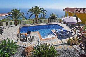 A swimming pool with a view of the sea, surrounded by a white fence, and includes a table and chairs. - Villa La Hoya en Tijarafe (Tijarafe)