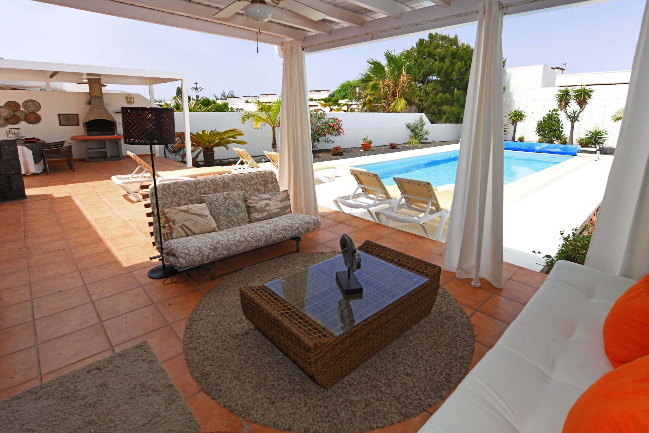 Une terrasse extérieure avec une piscine, un canapé, une table et un barbecue.