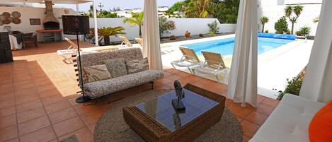 Une terrasse extérieure avec une piscine, un canapé, une table et un barbecue.