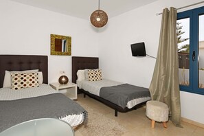 Ein Schlafzimmer mit zwei Betten, einem Fernseher, einem Spiegel und einem Fenster mit Vorhängen.