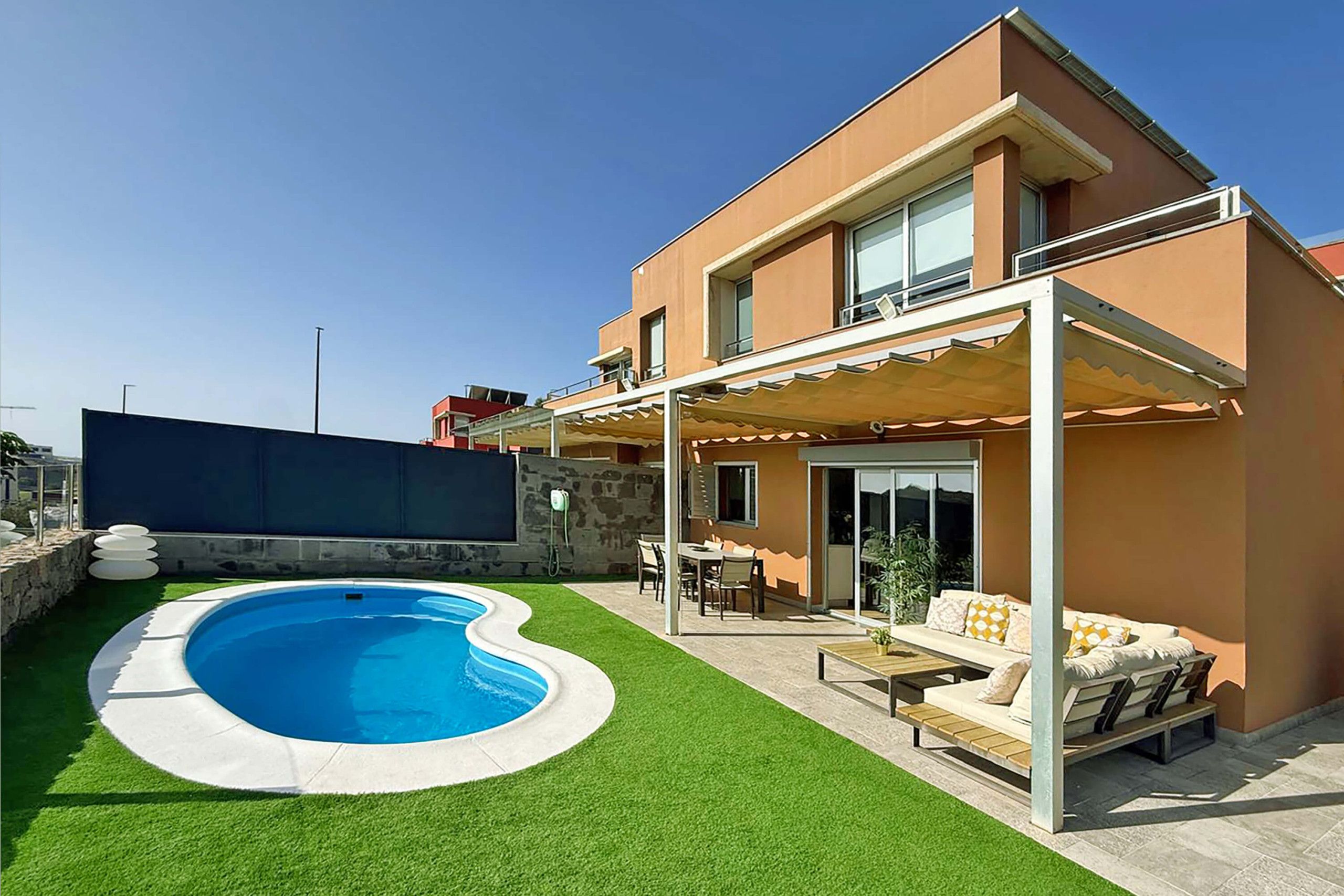 A modern two-story house with a swimming pool, outdoor seating, and a covered patio.