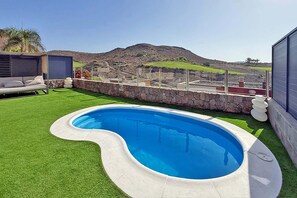 Piscina com muro de pedra e vista para montanha.