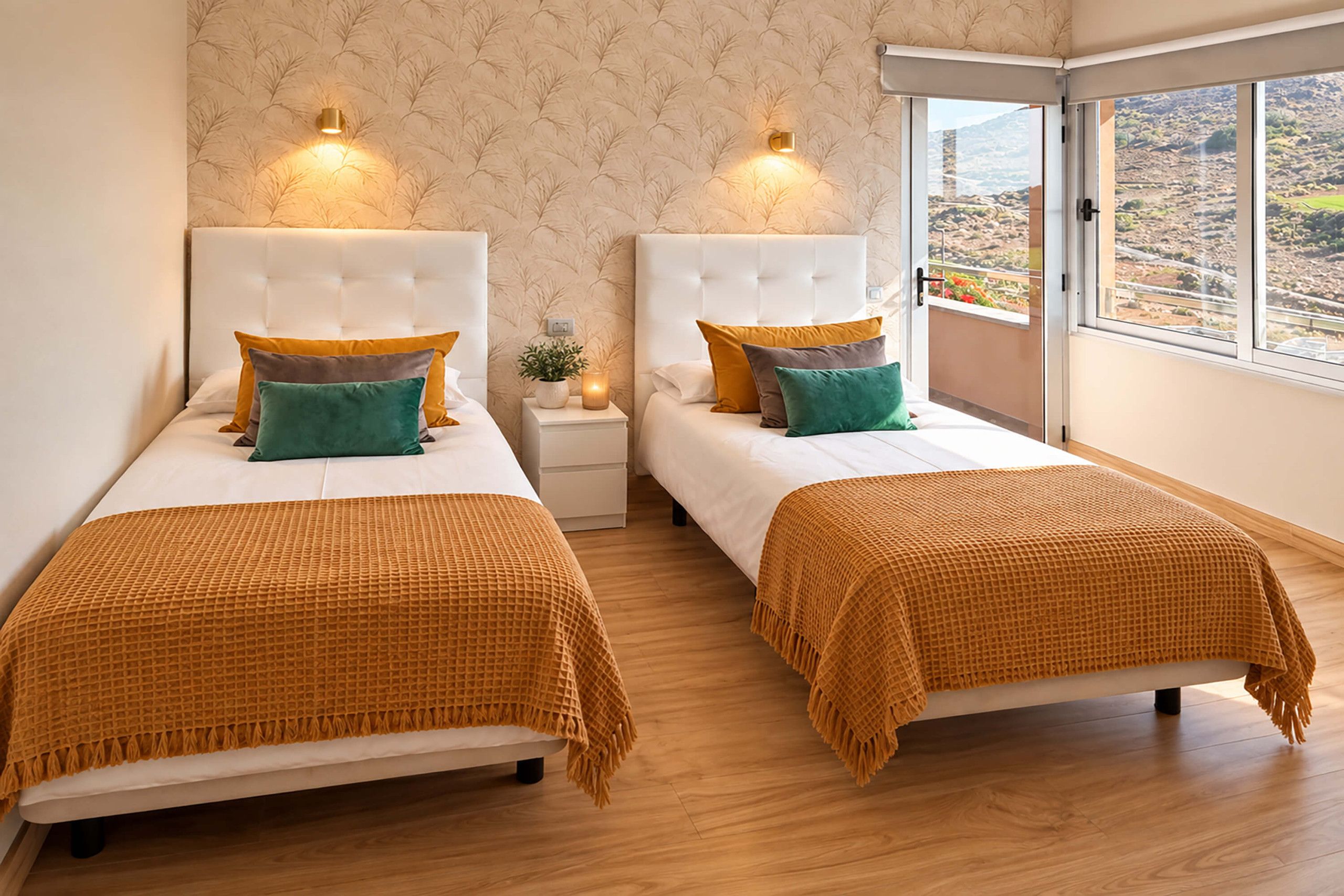 A hotel room with two beds, a nightstand, a potted plant, and a view of a mountainous landscape through a large window.