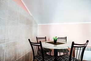 Un comedor con una mesa redonda, cuatro sillas y una planta en maceta.