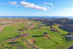 Ein Golfplatz mit freiem Blick auf das Meer und die entfernten Hügel.