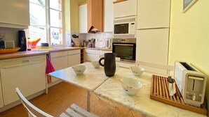 Una cocina con alacenas blancas, microondas, horno, cafetera y tostadora.