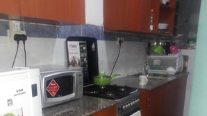 Una cocina compacta con microondas, estufa y un refrigerador pequeño.
