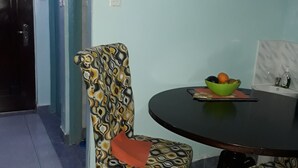 Un comedor con una silla estampada, una mesa redonda y un calendario en la pared.