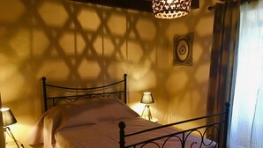 Una cama bien hecha con estructura metálica, dos lámparas de noche y un aplique de pared.