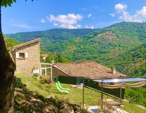 Ein Haus aus Stein mit einem Ziegeldach, einer grünen Rutsche und Solaranlagen.
