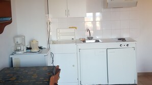 A compact kitchen with white cabinets, a built-in sink, and a small countertop. - Apartment with a view (Palaia Epidavros)